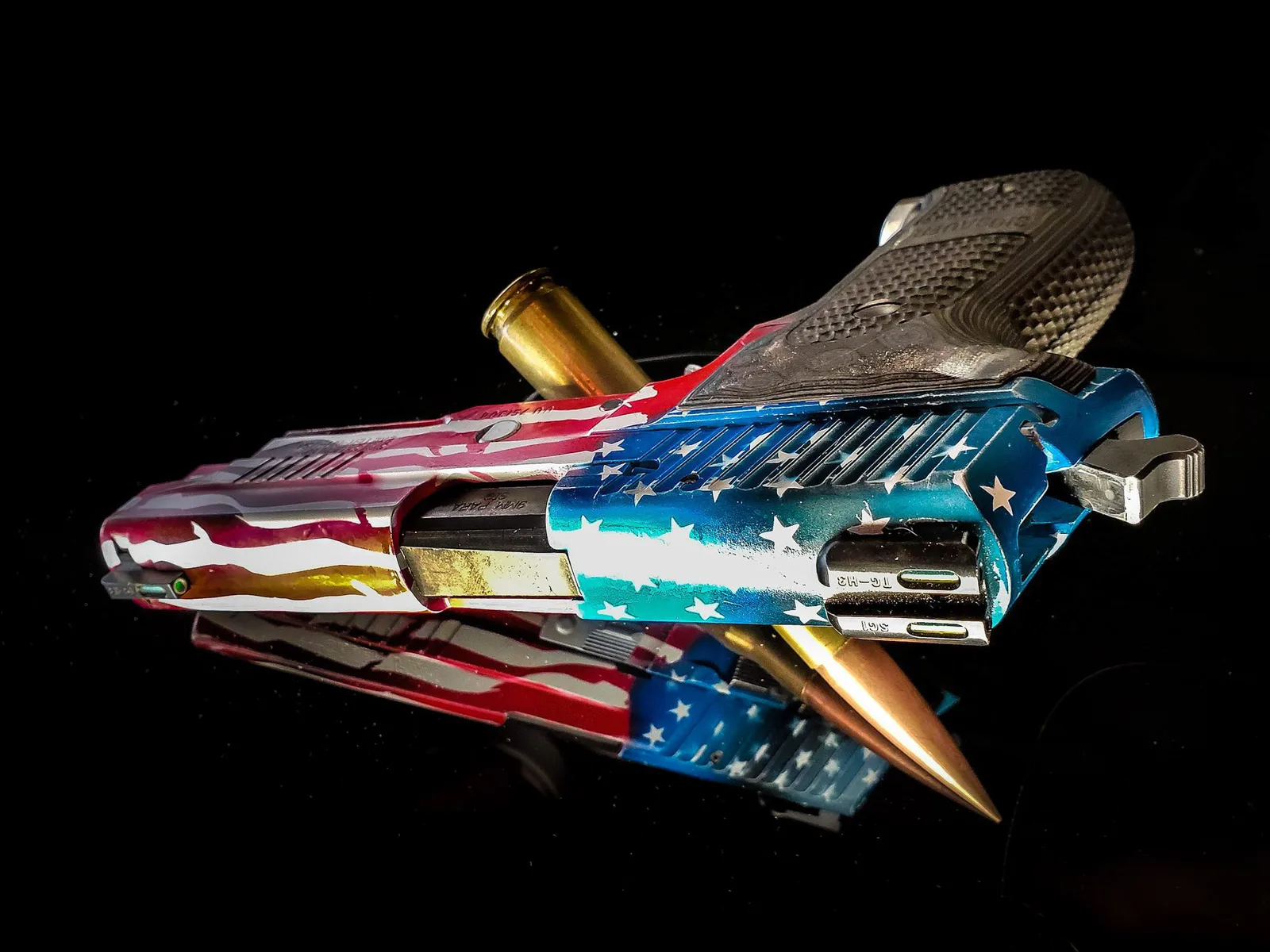 1911 pistol with a distressed American flag Cerakote finish on a black reflective surface.