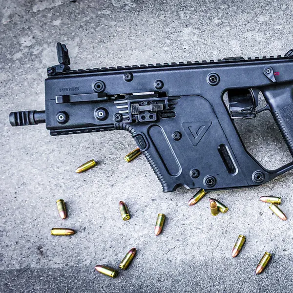 KRISS Vector carbine in a solid black finish on concrete with scattered 9mm rounds.
