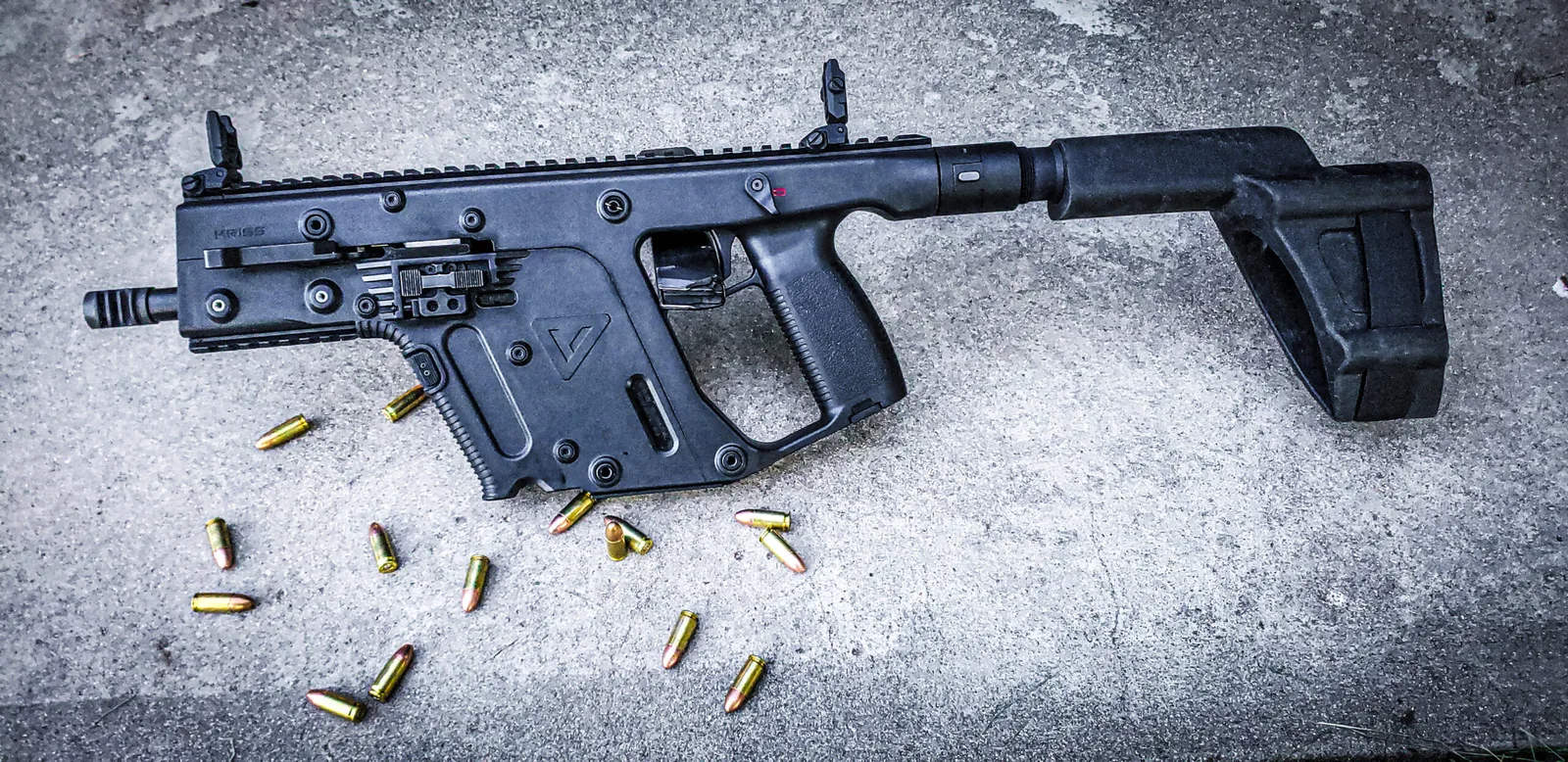 KRISS Vector carbine in a solid black finish on concrete with scattered 9mm rounds.