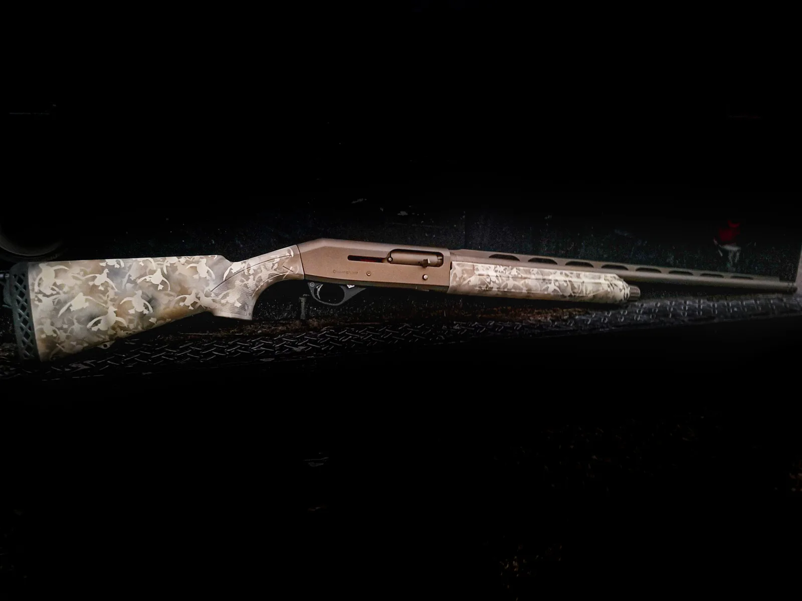 Semi-automatic shotgun with a burnt bronze receiver and light camo stock in Cerakote.